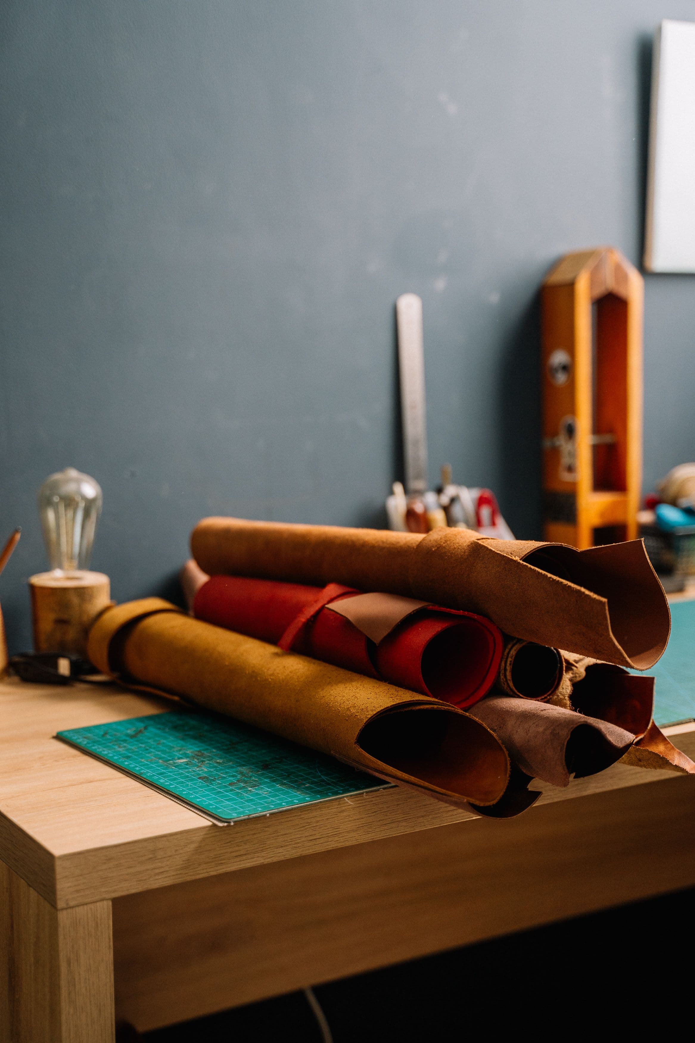 Rolls of leather and tools on a workshop cutting table